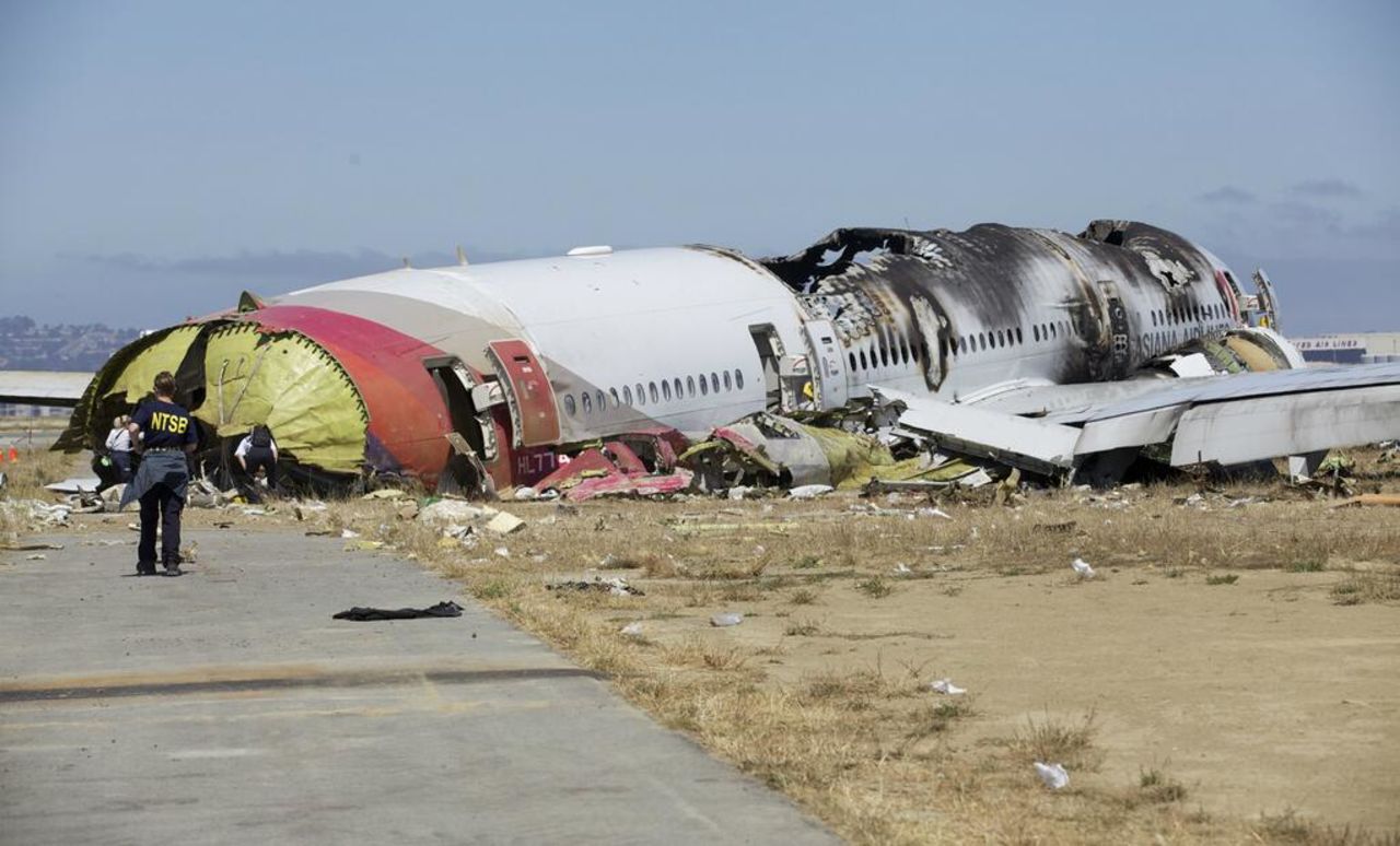An investigator stands near the tail of the plane in a handout photo released on July 7. The NTSB has ruled out weather as a problem and said that conditions were right for a "visual landing."