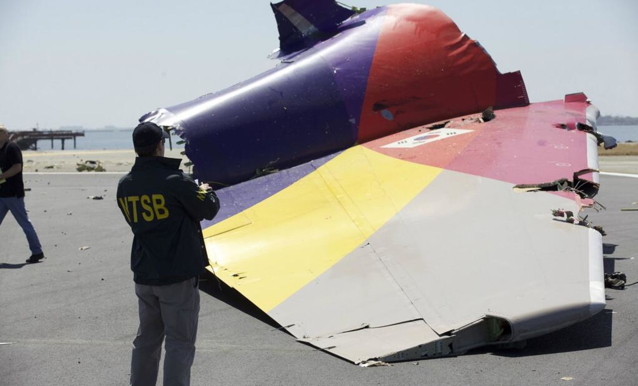An investigator inspects the broken-off tail of the plane in a handout photo released July 7. The crash killed two people, injured 182 and forced the temporary closure of one of the country's largest airports.