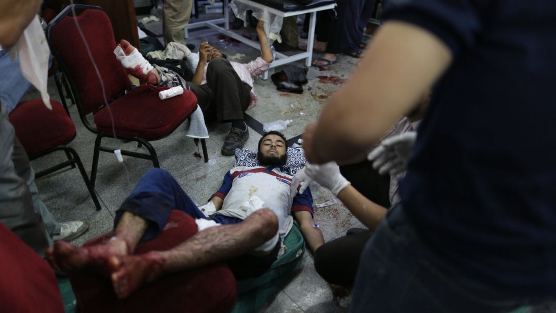 Injured men receive medical attention after clashes between supporters of Morsy and security forces in Cairo on July 8.