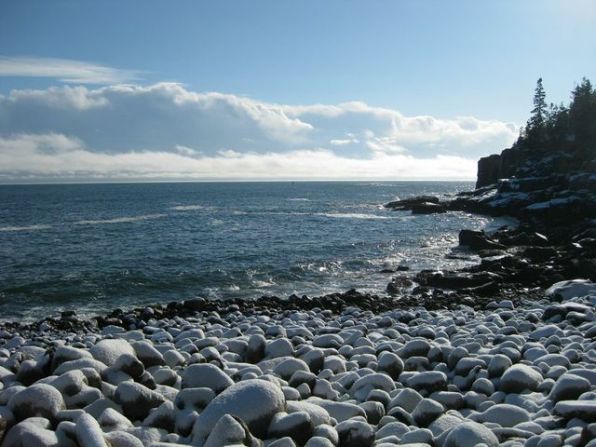 Otter Cliffs, noted for world-class rock climbing, overlooks a beach covered in cobblestones.