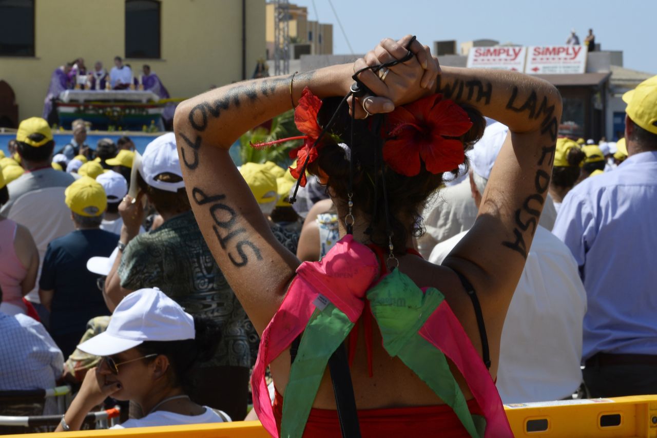 A faithful has "Stop clowning with Lampedusa" painted on her arms as the pope led  the mass. "The culture of well-being, that makes us think of ourselves, that makes us insensitive to the cries of others, that makes us live in soap bubbles, that are beautiful but are nothing, are illusions of futility, of the transient, that brings indifference to others, that brings even the globalization of indifference," said Pope Francis. <br />