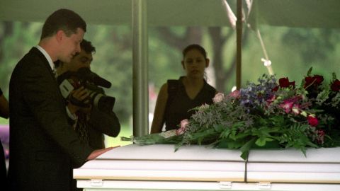 Russell Yates places his hand on the casket of one of his deceased children during their funeral on June 27, 2001, at Forest Park East Cemetery in Houston. On July 30, 2004, he filed for divorce from Andrea.