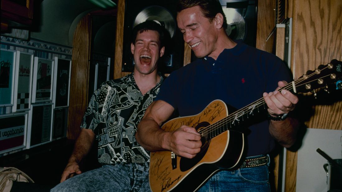 Travis laughs with Arnold Schwarzenegger in 1990.