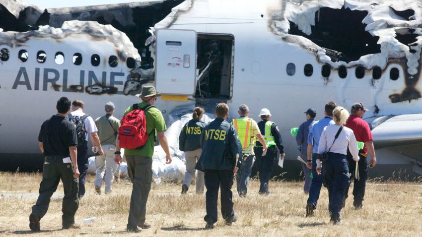 In this handout photo provided by the National Transportation Safety Board, NTSB investigators examine the wreckage of Asiana Airlines flight 214 following yesterday's crash, on July 7, 2013 in San Francisco, California. 