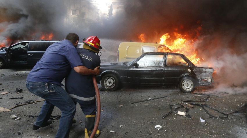 A firefighter is helped as he extinguishes fire at the site of an explosion in Beirut's southern suburb neighbourhood of Bir al-Abed on July 9, 2013.