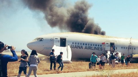 Several passengers can be seen escaping Asiana Airlines flight 214 with their carry-on luggage.