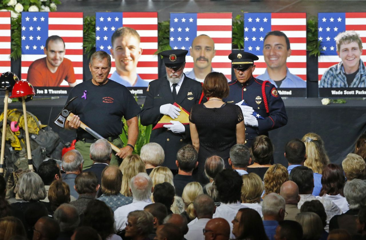 An honor guard presents a family member with an American flag during a memorial service in Prescott Valley, Arizona, on Tuesday, July 9. <a href="http://www.cnn.com/interactive/2013/07/us/yarnell-fire/index.html">Nineteen members of the Granite Mountain Hotshots</a> died Sunday, June 30, battling the Yarnell Hill wildfire.  