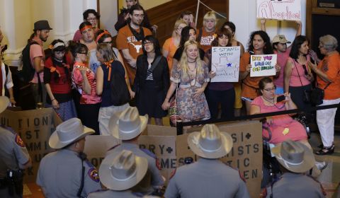 On October 28, 2013, the day before the legislation was scheduled to take effect, a federal judge ruled that parts of it were unconstitutional. Above, state troopers look on as a group in Austin, Texas, protests the law.