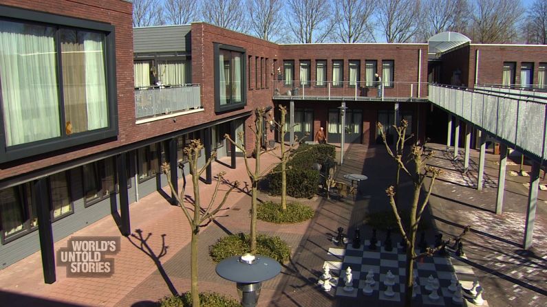 The two-story buildings form a courtyard where residents can roam on their own and where they are watched by carers, some of whom staff the site's shops.