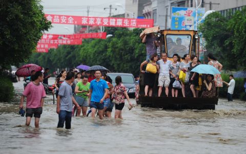 Residents travel on an excavator through flooded streets in Chengdu, the capital of Sichaun province, on July 9.