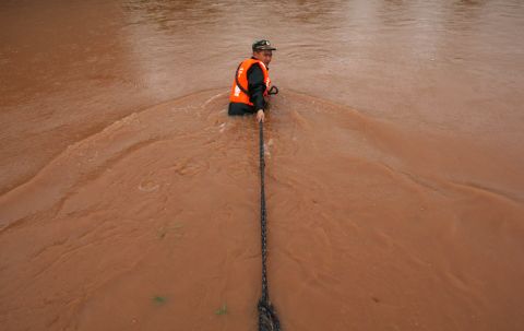 A rescuer pulls a ship in a flooded area of Suining city on Monday, July 1.