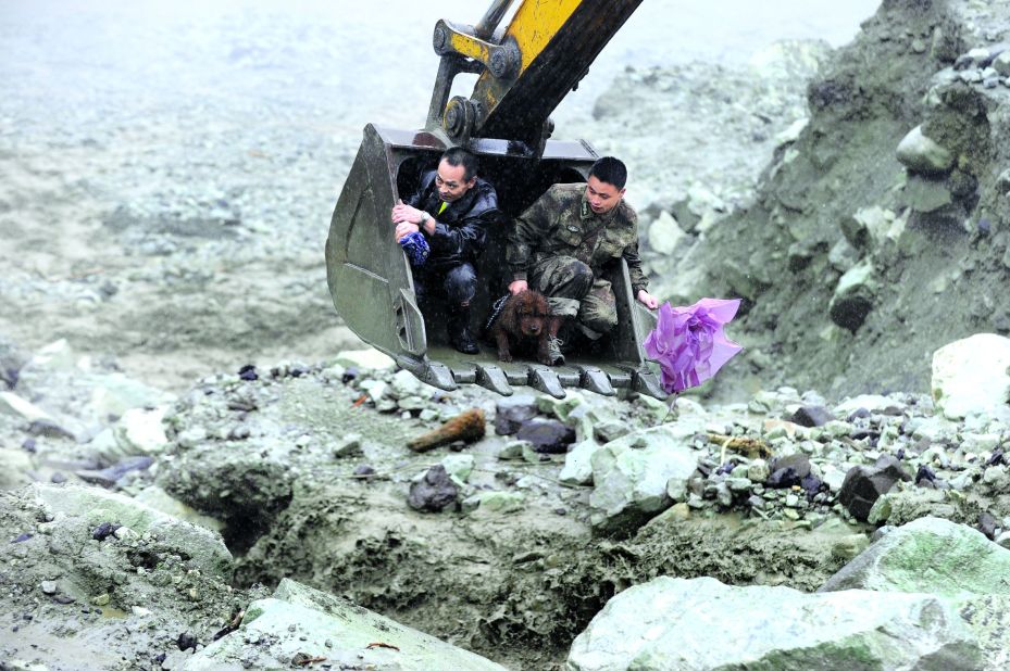 Rescuers evacuate residents with an excavator on Wednesday, July 10, after a landslide hit Wenchuan, China. Flooding that triggered the landslide reportedly has affected 1.5 million people.