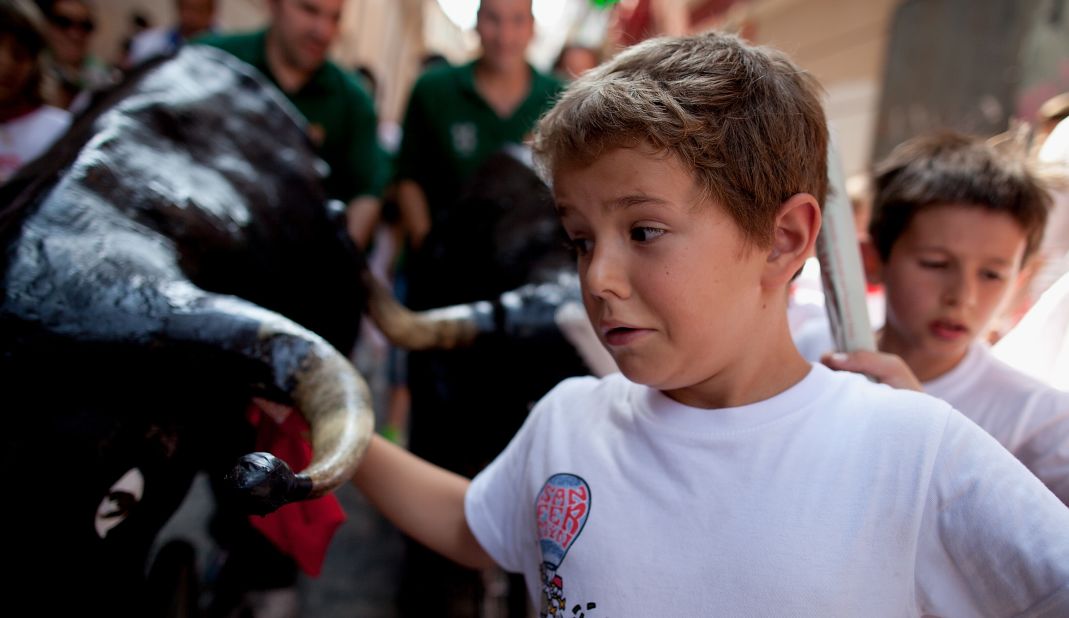 Children run in front of a toy bull during the Little Bull Run, at the San Fermin running of the bulls festival, on Friday, July 12, in Pamplona, Spain. 