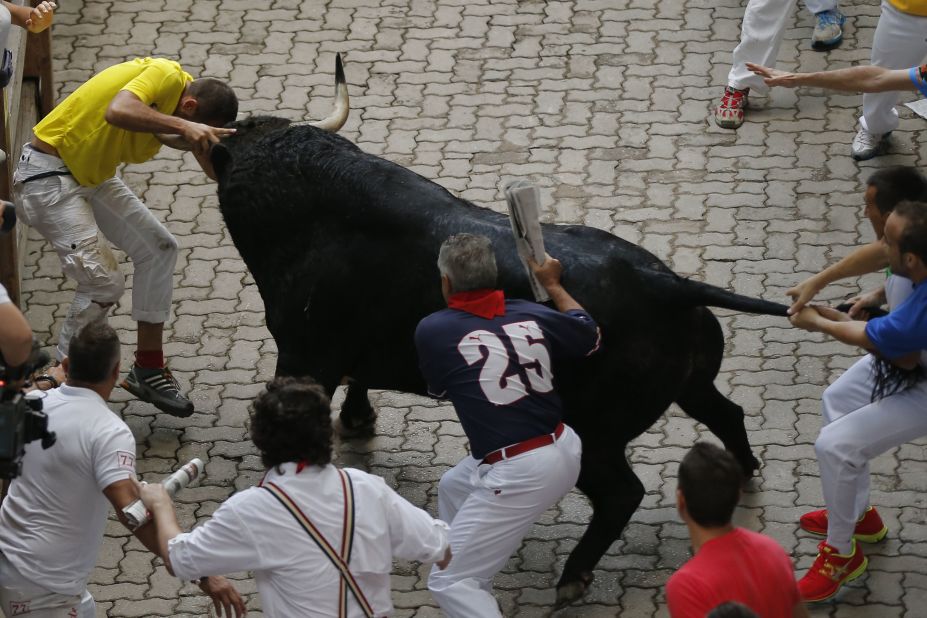 A bull attacks a man while other participants try to pull the bull away on July 12. Thrill-seekers from around the globe descend on the Spanish town every year to test their bravery. 