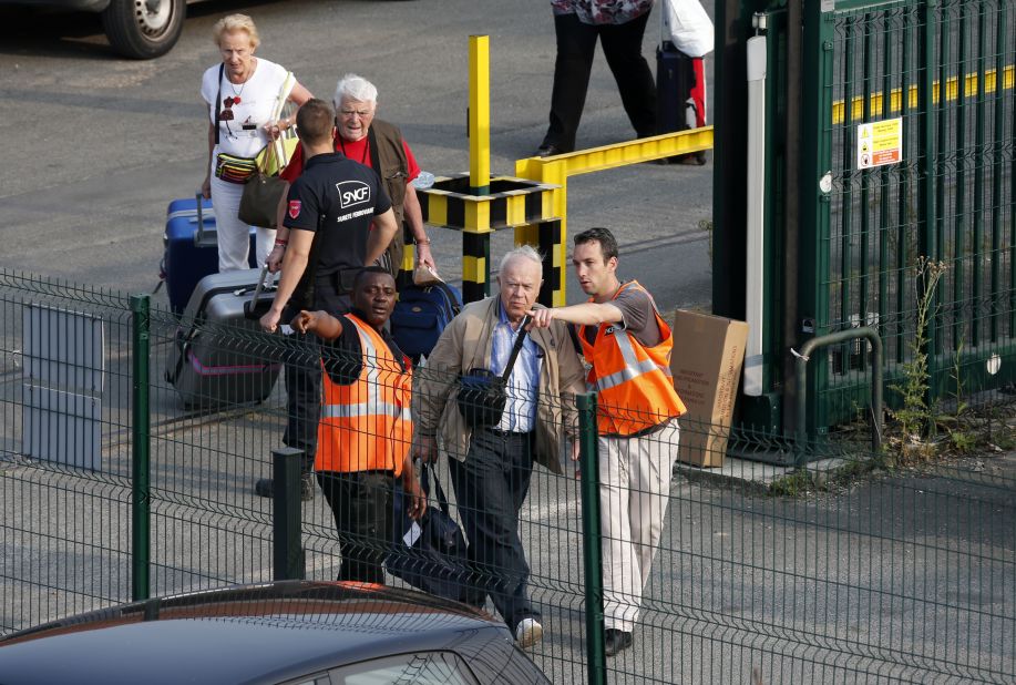Passengers are escorted from the scene by French railway employees on July 12.