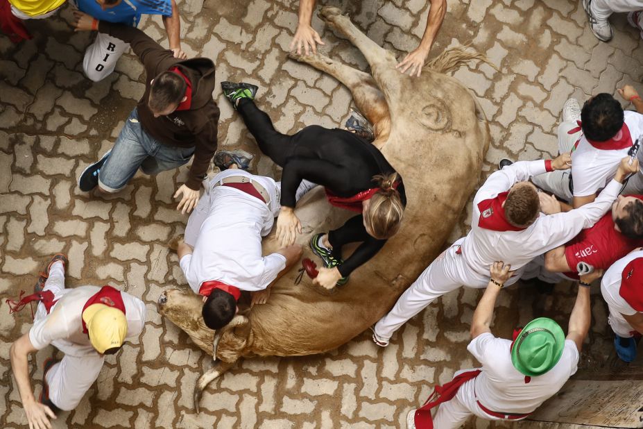 Runners stumble and trip over a fallen bull on July 13. 