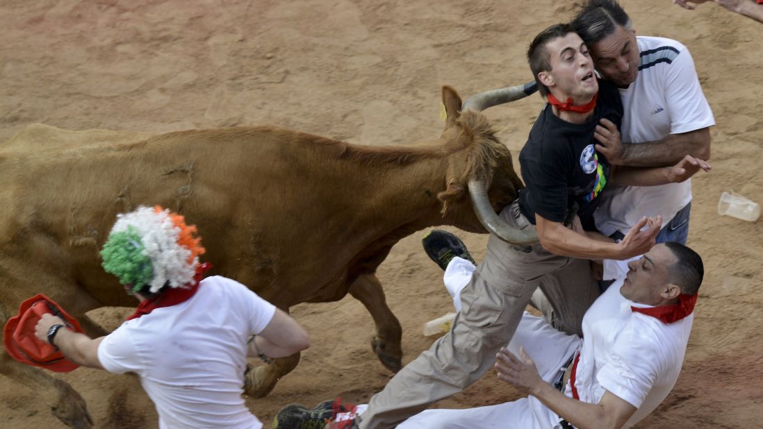 People are pushed by a bull in the bull ring in Pamplona on July 14.