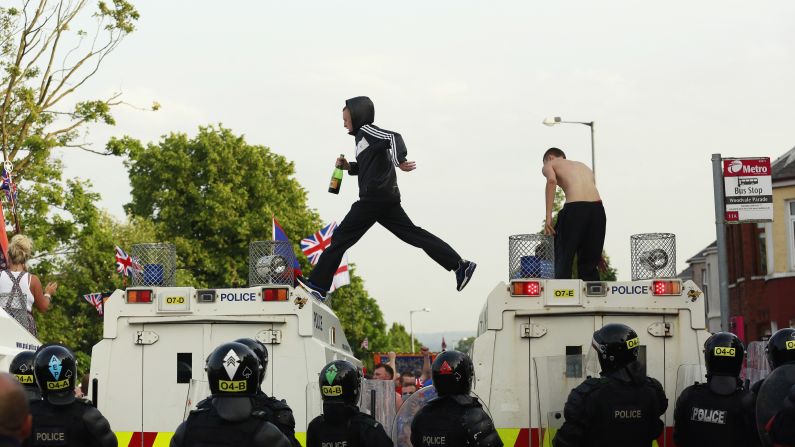 Protesters climb onto police vehicles in the Woodvale Road area of Belfast on July 12.