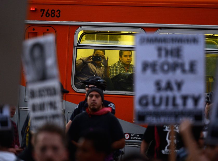 A passenger takes a picture of protesters as he rides a city bus on July 16 in Los Angeles.