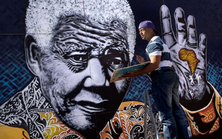 South African artist John Adams works on a giant painting of <a >Nelson Mandela</a> in a suburb of Johannesburg. Mandela, an anti-apartheid icon and Nobel peace laureate, endured 27 years in prison before becoming South Africa's first democratically elected president. Click through the gallery for other artistic tributes to "the world's most famous political prisoner."