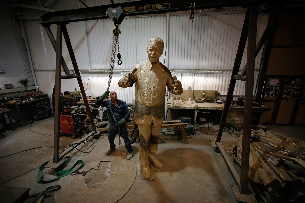 <strong>ENGLAND: </strong>A foundry worker moves a crane after lifting a new statue of Mandela in Braintree, northeast of London. The nine-foot high bronze statue was started by British sculptor Ian Walters, who died in 2006, and completed by Nigel Boonham. Weighing approximately one ton, the sculpture now stands on the corner of Parliament Square facing the Palace of Westminster.