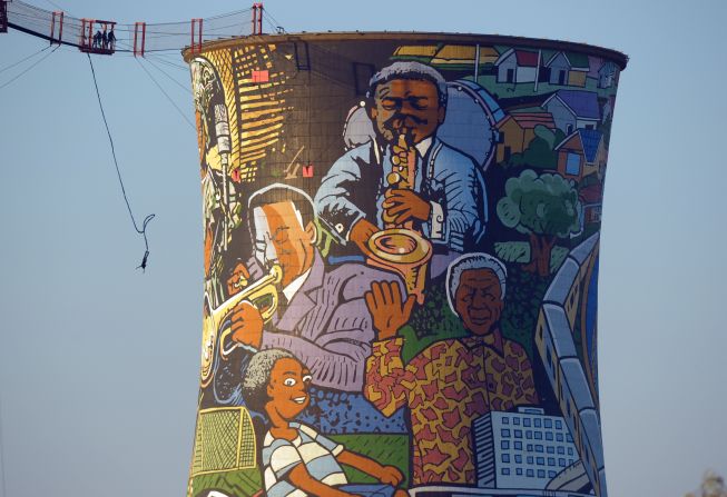 <strong>SOUTH AFRICA: </strong>A person bungee jumps off old cooling towers in Soweto painted with a mural featuring Mandela.