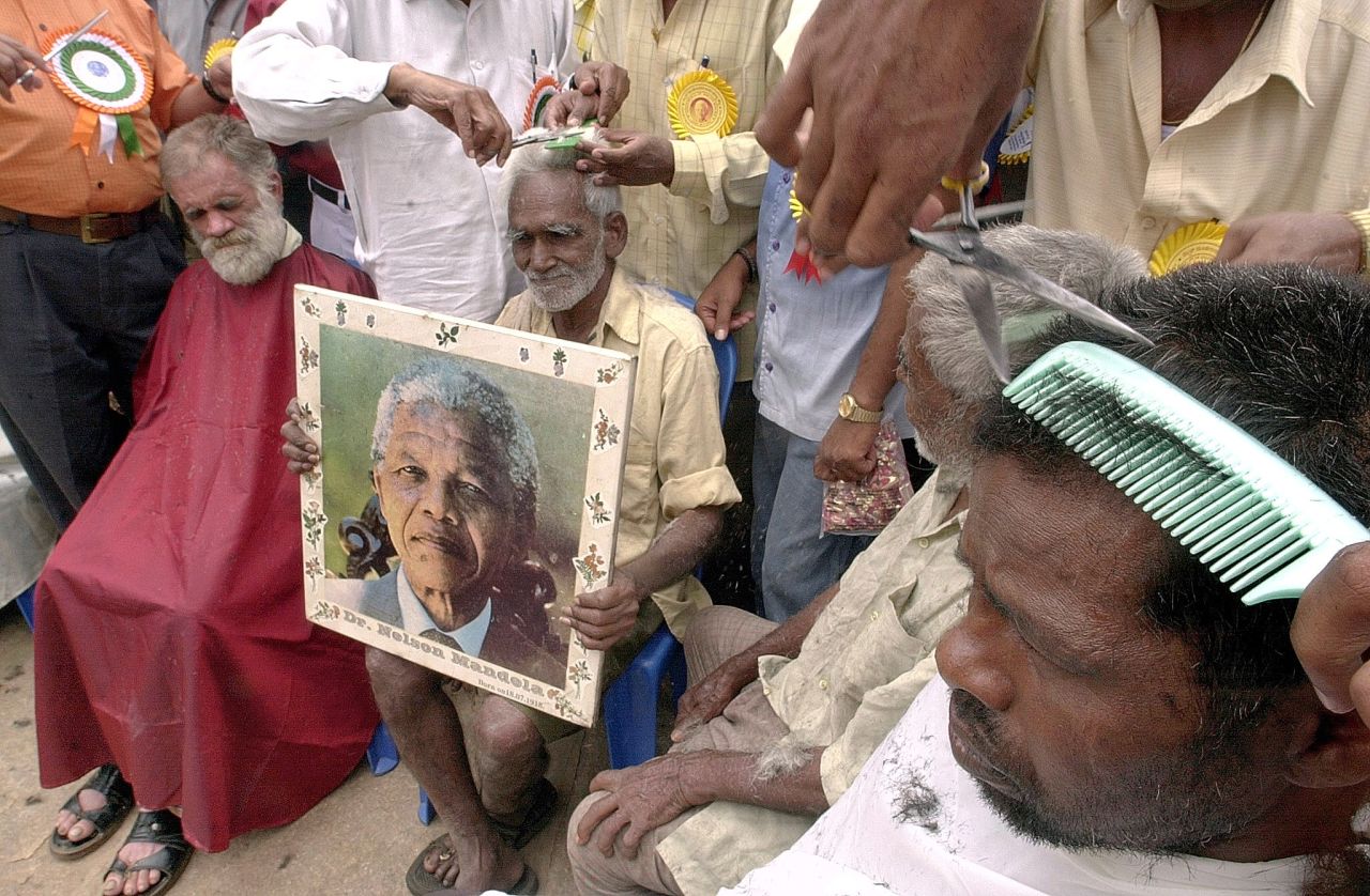 <strong>INDIA:</strong> An elderly man in Bangalore holds a portrait of Mandela as he receives a free haircut to commemorate the 84th birthday of the former South African president in 2002.