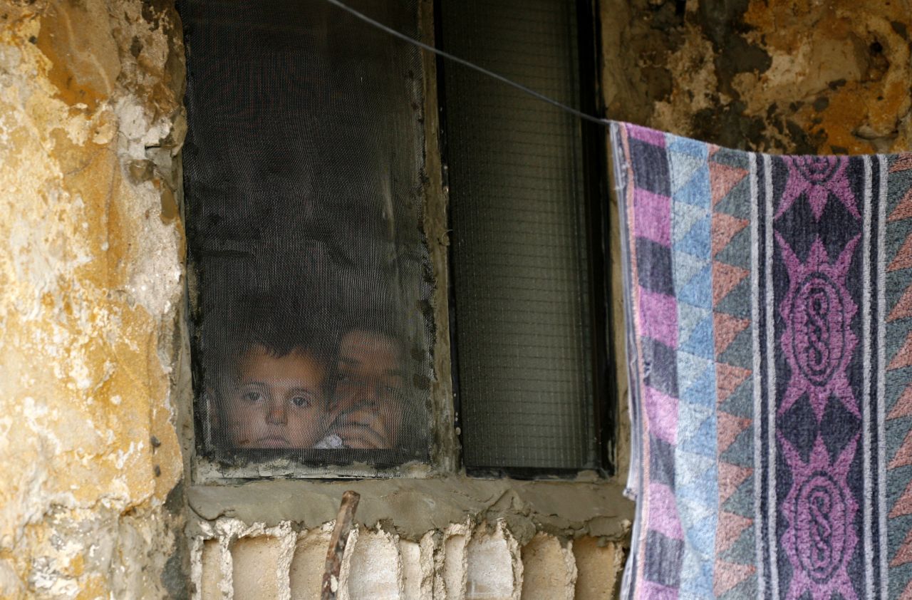 A Syrian woman and child look out of a refugee camp window in Alman, Lebanon, in June 2013.