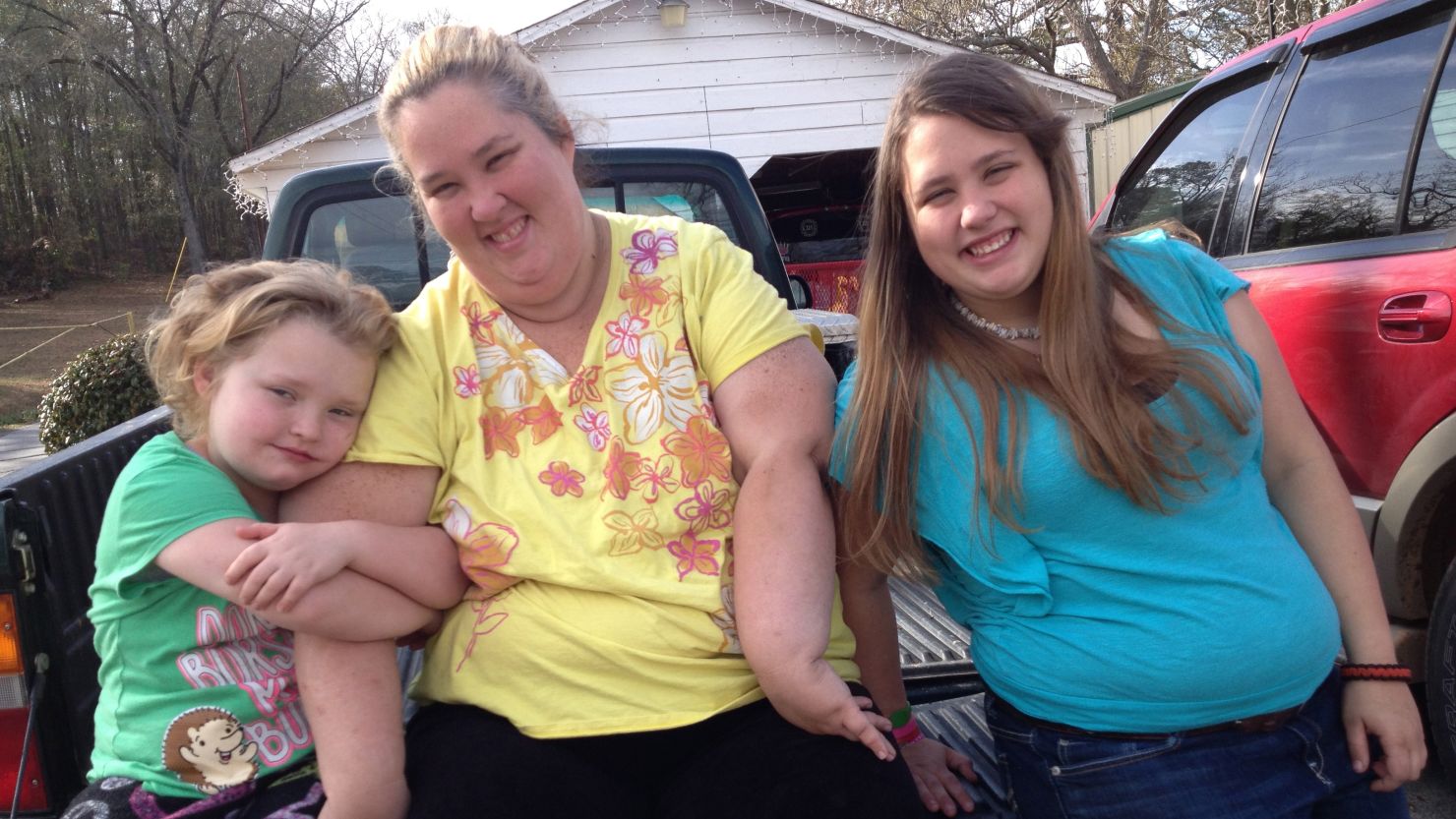 Honey Boo Boo (Alana Thompson), Mama (June Shannon), and Chubbs (Jessica Shannon) sitting on a pickup truck bed.