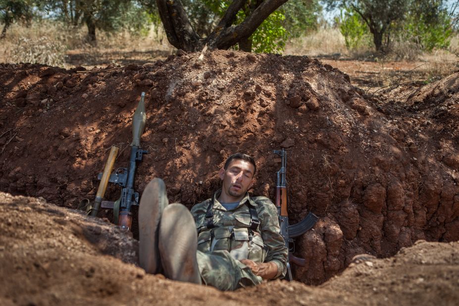 A rebel fighter naps in a trench about 300 feet from the Syrian government forces' positions along the highway connecting Idlib with Latakia on Monday, July 15.