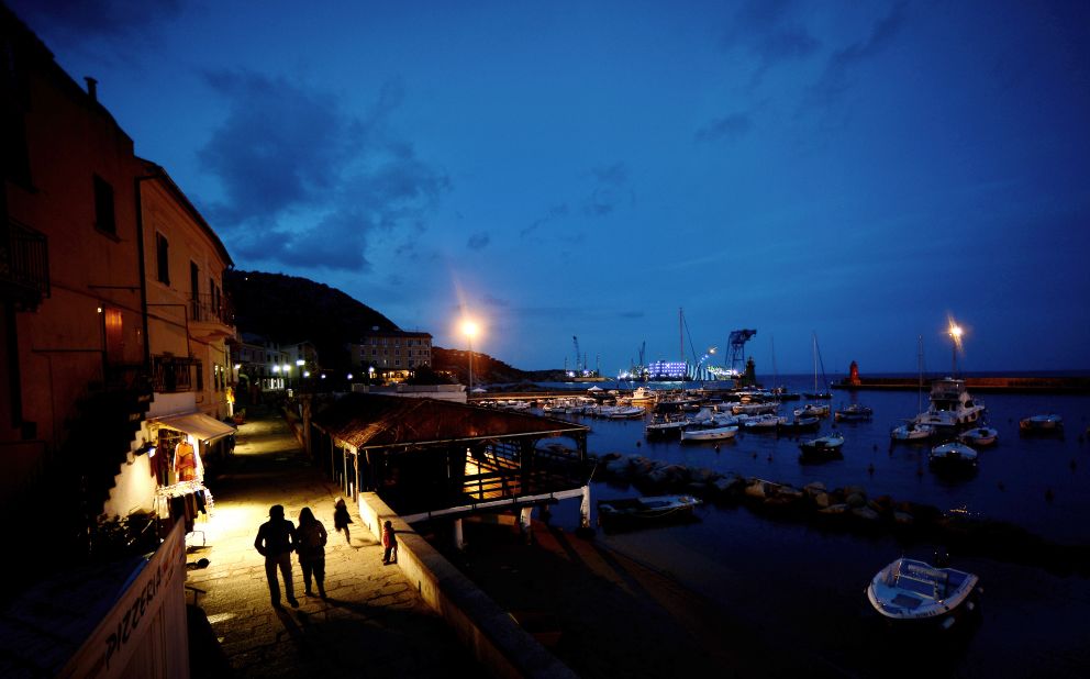 A couple walks along the port of Giglio at night on January 12, 2013.