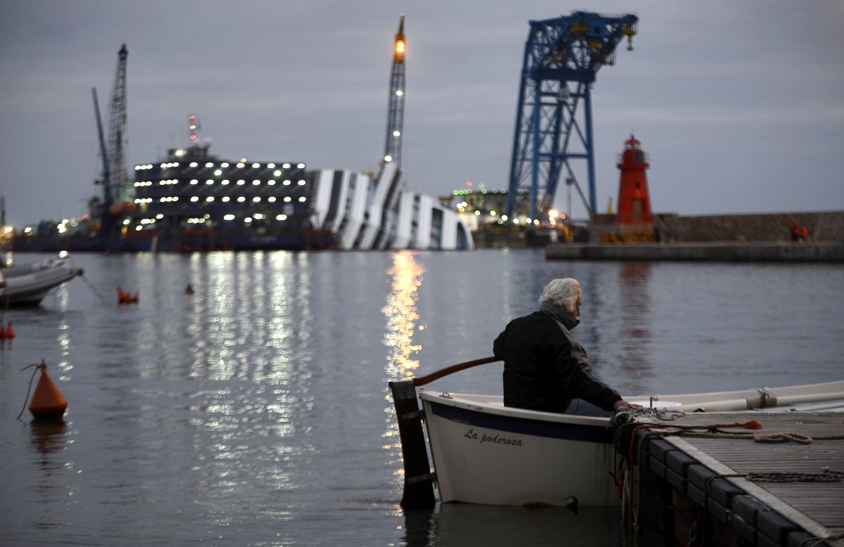 Un hombre rema en su bote frente al sumergido crucero el 8 de enero de 2013.