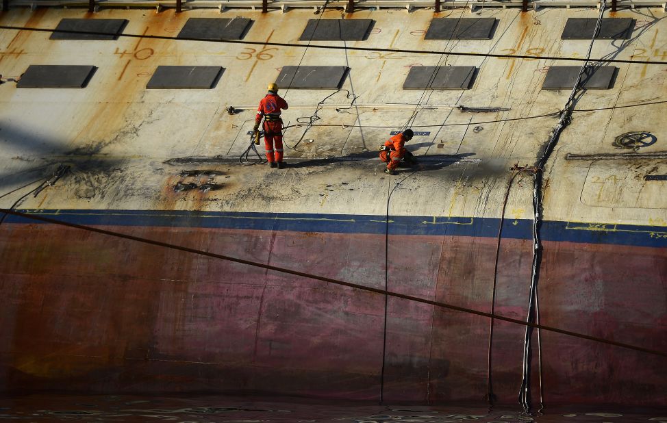 Workers stand on the edge of the ship on January 8, 2013.