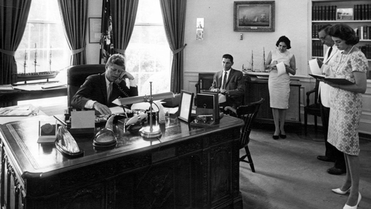 Thomas, third right, takes notes as President John F. Kennedy speaks on the phone in the Oval Office on August 23, 1962.
