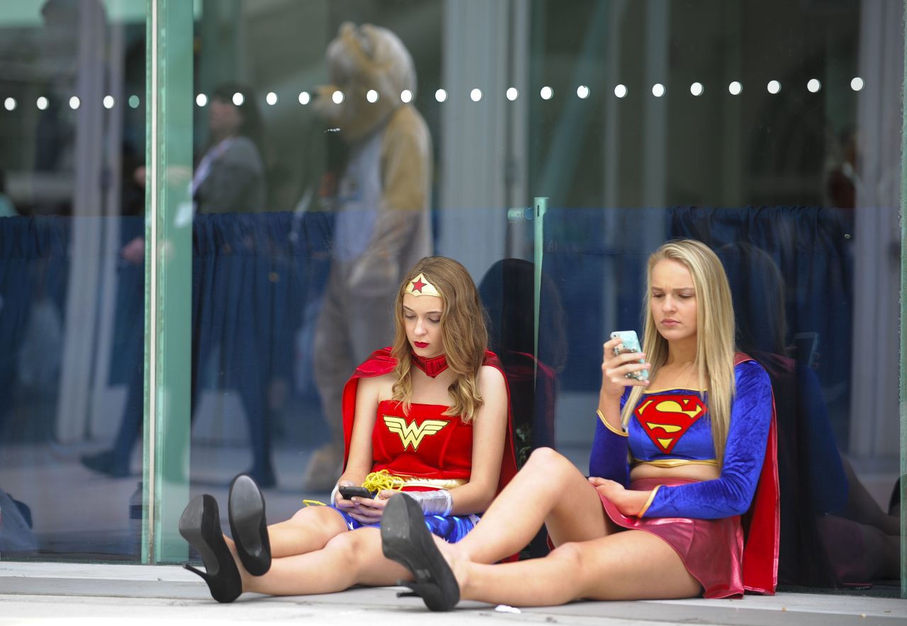 Joy Donaldson, left, dressed as Wonder Woman, and Everleigh Reed as Supergirl, take a break outside of the convention on July 20.