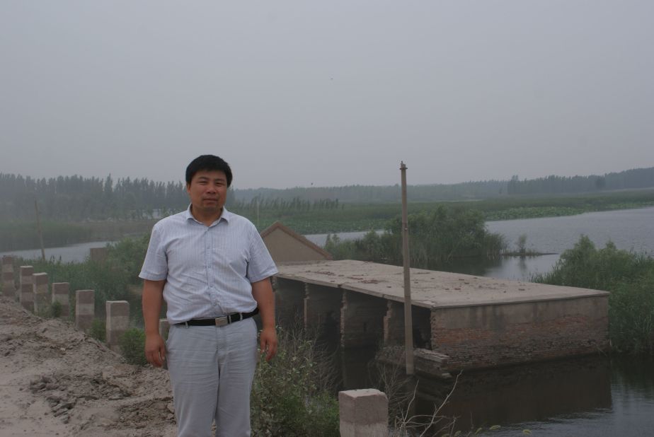 Xiao Guoqiang, a 50-year-old farmer stands before his sunken village in Jining, Shandong Province on June 26, 2013. Underground mining in this region is devouring 20 million square meters of land a year.