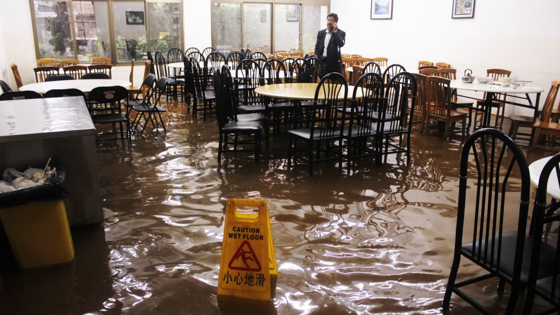 A man tries to make a phone call on Friday, July 19, in a flooded restaurant in Kunming, China, in the wake of Typhoon Soulik. 