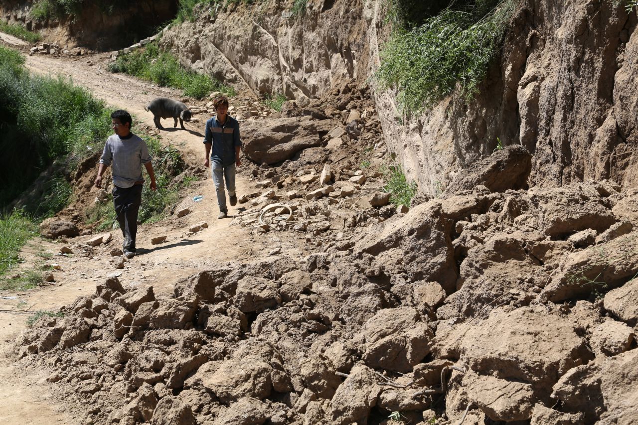 Two men make their way along a damaged road in Hetuo township in Dingxi on July 22.  The original quake and powerful aftershocks caused roofs to collapse, cut telecommunications lines and damaged a major highway linking Gansu Province's capital of Lanzhou to the south, reports say.