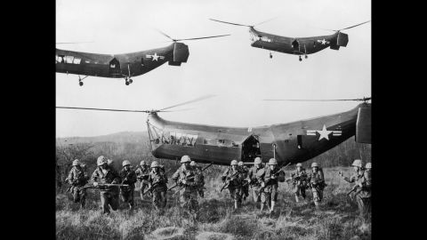 U.S. troops emerge from helicopters onto an open field, circa 1953.