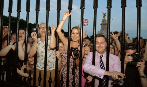 Crowds gathered outside Buckingham Palace cheer as Anderson places the birth announcement in front of the palace on July 22. 