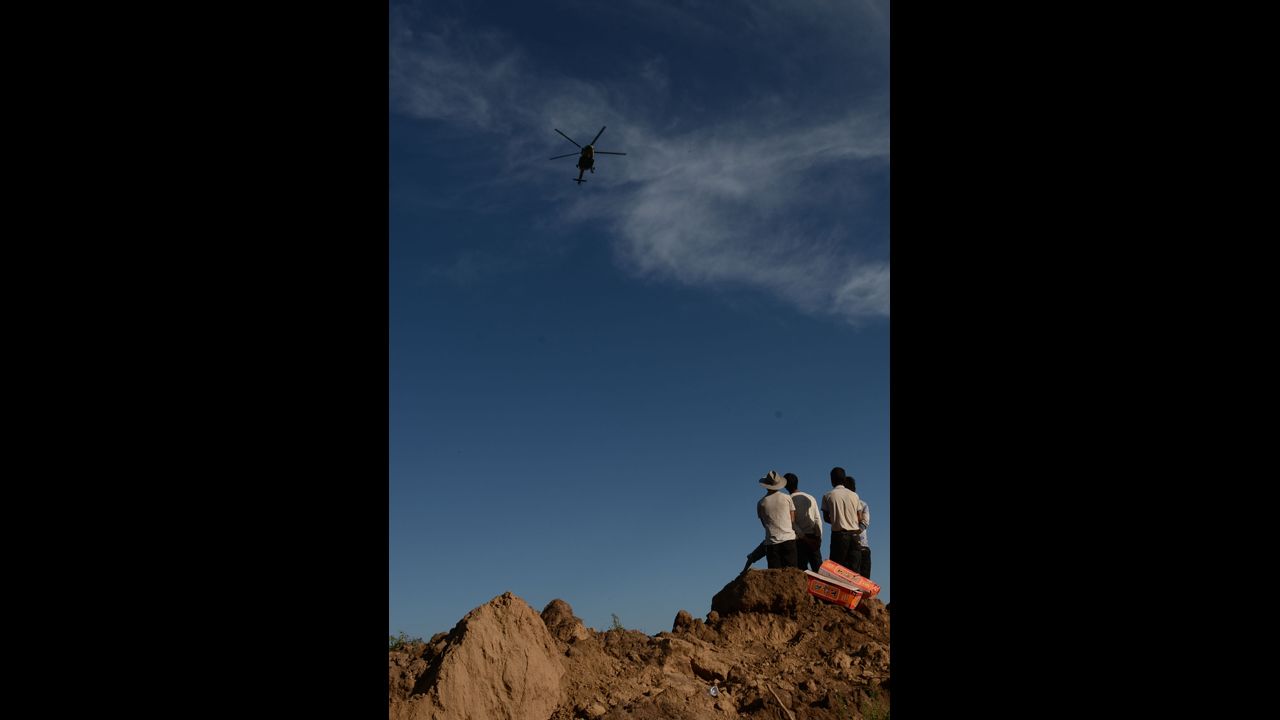 A helicopter airdrops relief supplies above Yongguang on July 22 as villagers wait on the ground.