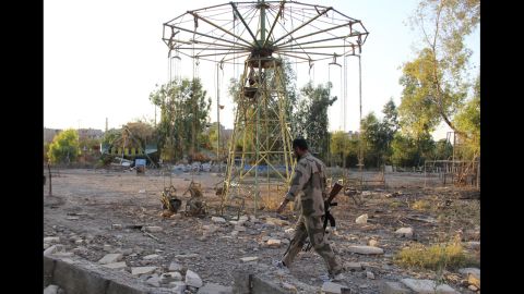 A rebel fighter walks past swings in a deserted playground in Deir al-Zor, Syria, on Sunday, July 21.