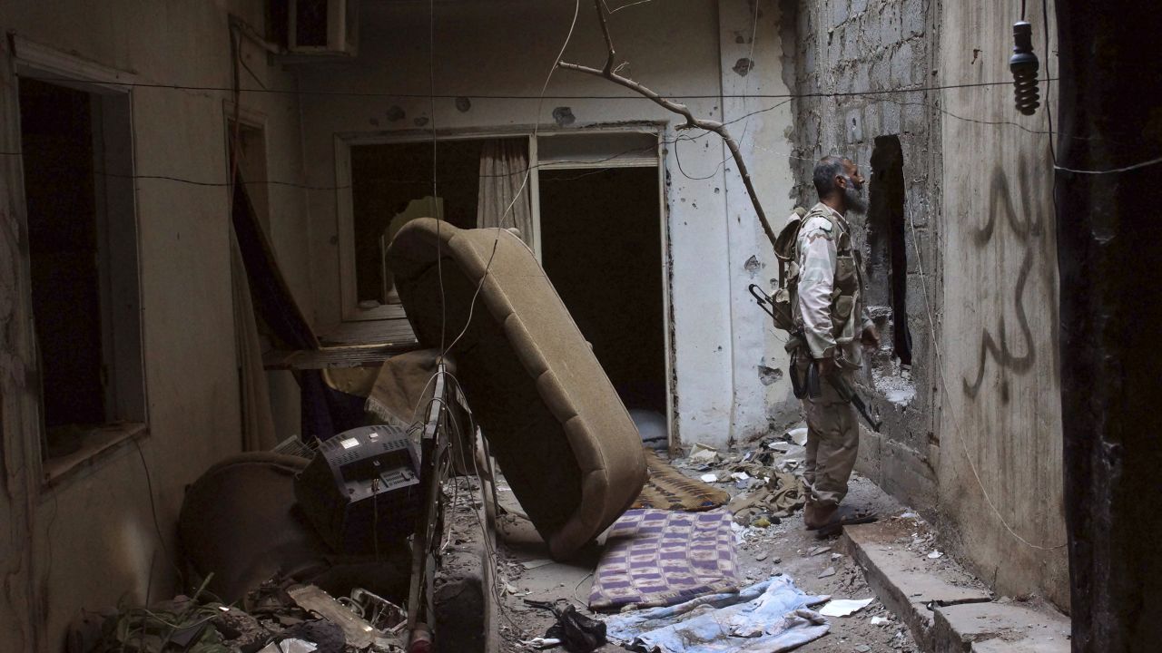 A rebel fighter speaks with a fellow fighter through a hole in a wall in Deir al-Zor on July 21.