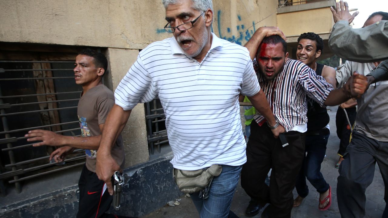 A man with a pistol and other Morsy opponents detain a suspected Morsy supporter who was wounded during clashes in Cairo on Monday, July 22. Supporters and opponents clashed near the city's Tahrir Square.
