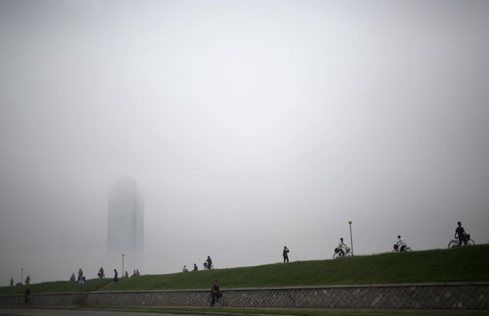 People make their way past a building clouded by a thick layer of mist on Monday, July 22, after torrential rain in Pyongyang, North Korea.