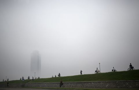 People make their way past a building clouded by a thick layer of mist on Monday, July 22, after torrential rain in Pyongyang, North Korea.