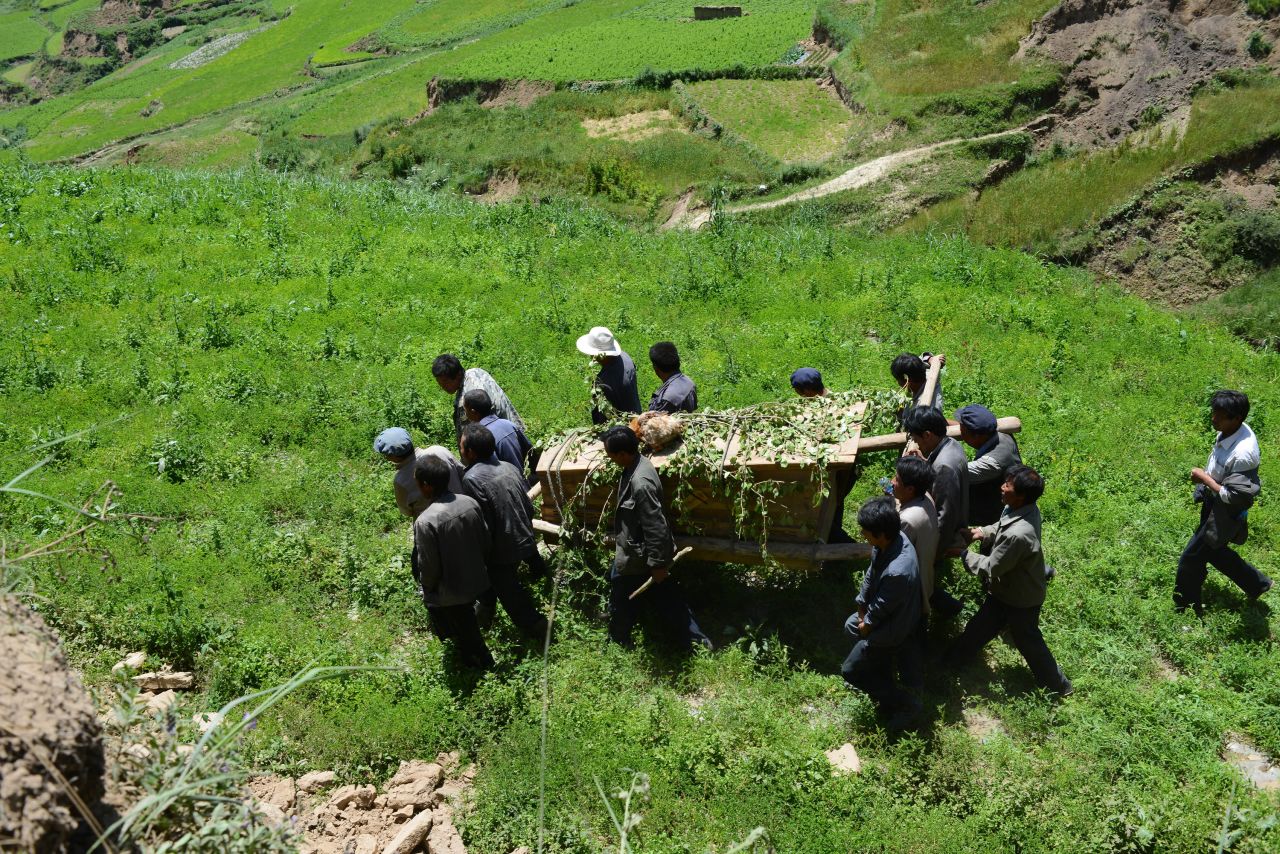 People carry a coffin July 23 during a funeral for an 84-year-old villager from Lalu who was killed in the earthquake. The death toll has risen to 94, local authorities said Tuesday.