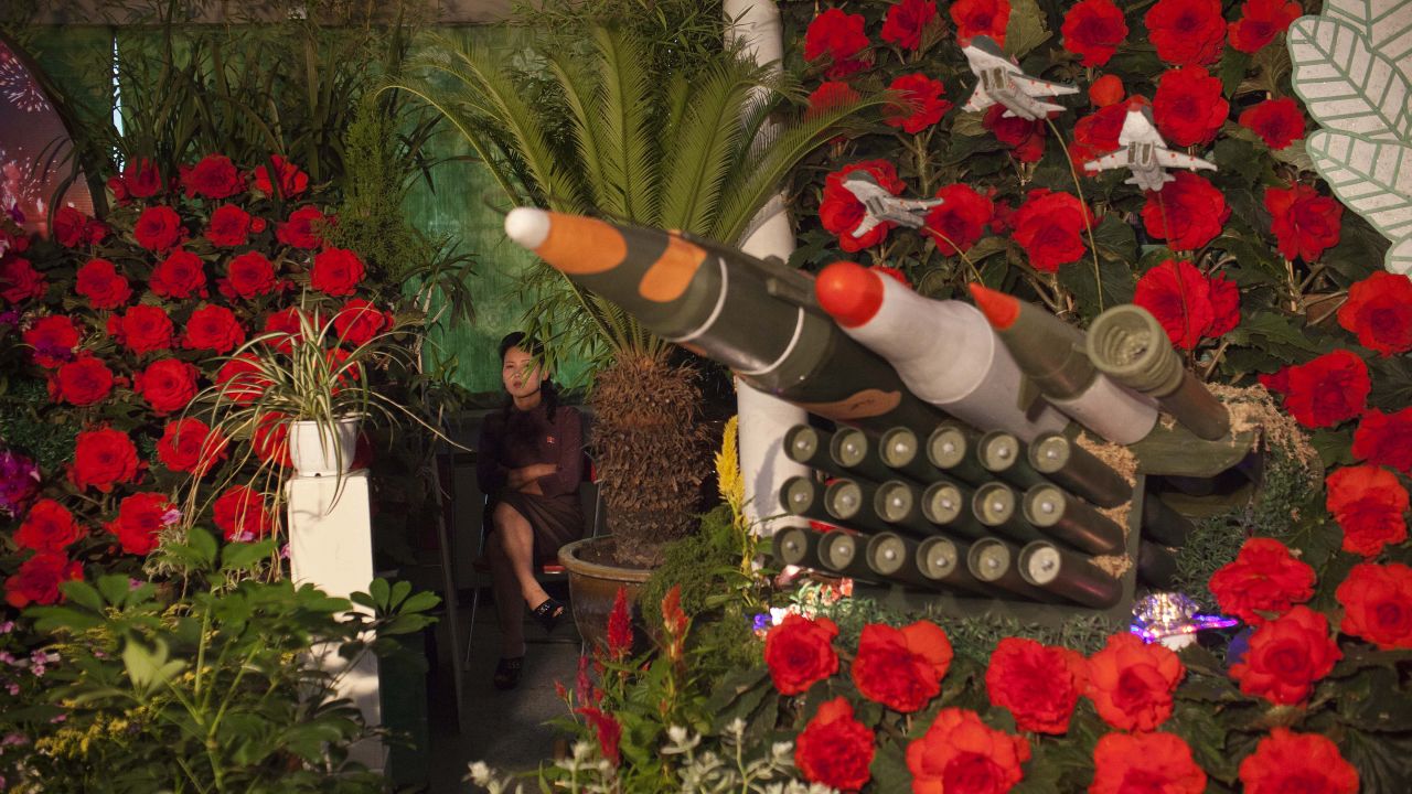 A woman sits next to models of military weapons at a festival for the "Kimilsungia" and "Kimjongilia" flowers, named after the country's late leaders, on Wednesday, July 24, in Pyongyang, North Korea. The exhibition was held to mark the 60th anniversary of the signing of the armistice agreement that ended the fighting on July 27, 1953.
