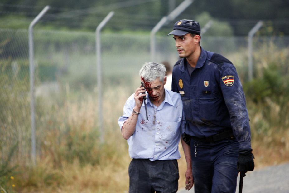Train driver Francisco Jose Garzon, identified by Spanish newspapers El Pais and El Mundo, is helped from the scene by a police officer.