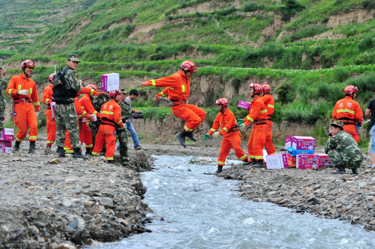A rescuer jumps over a creek as a team brings relief supplies for earthquake victims to Digu village on July 24.